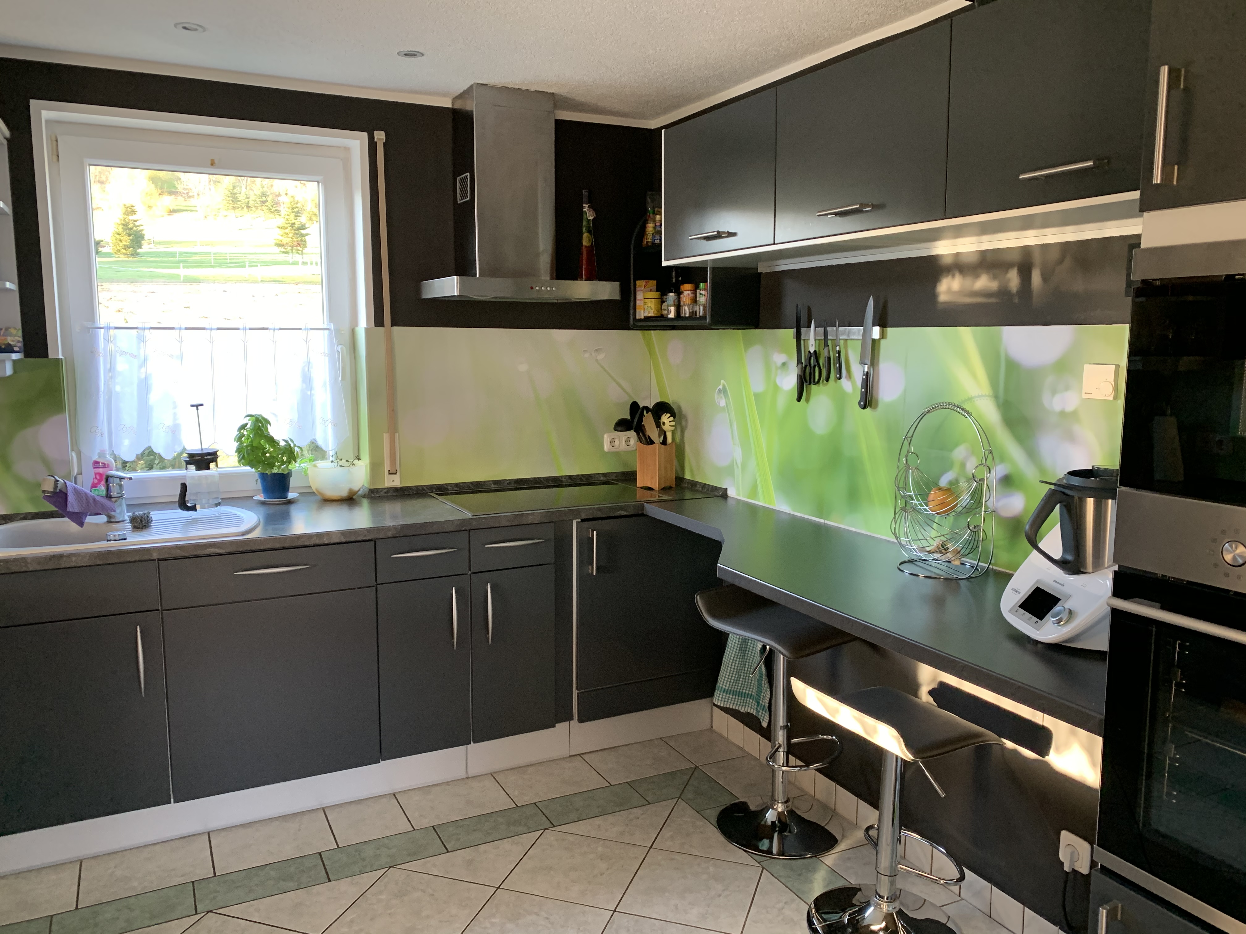Dunkle Küche mit stilvoller Küchenrückwand mit grünen Akzenten.