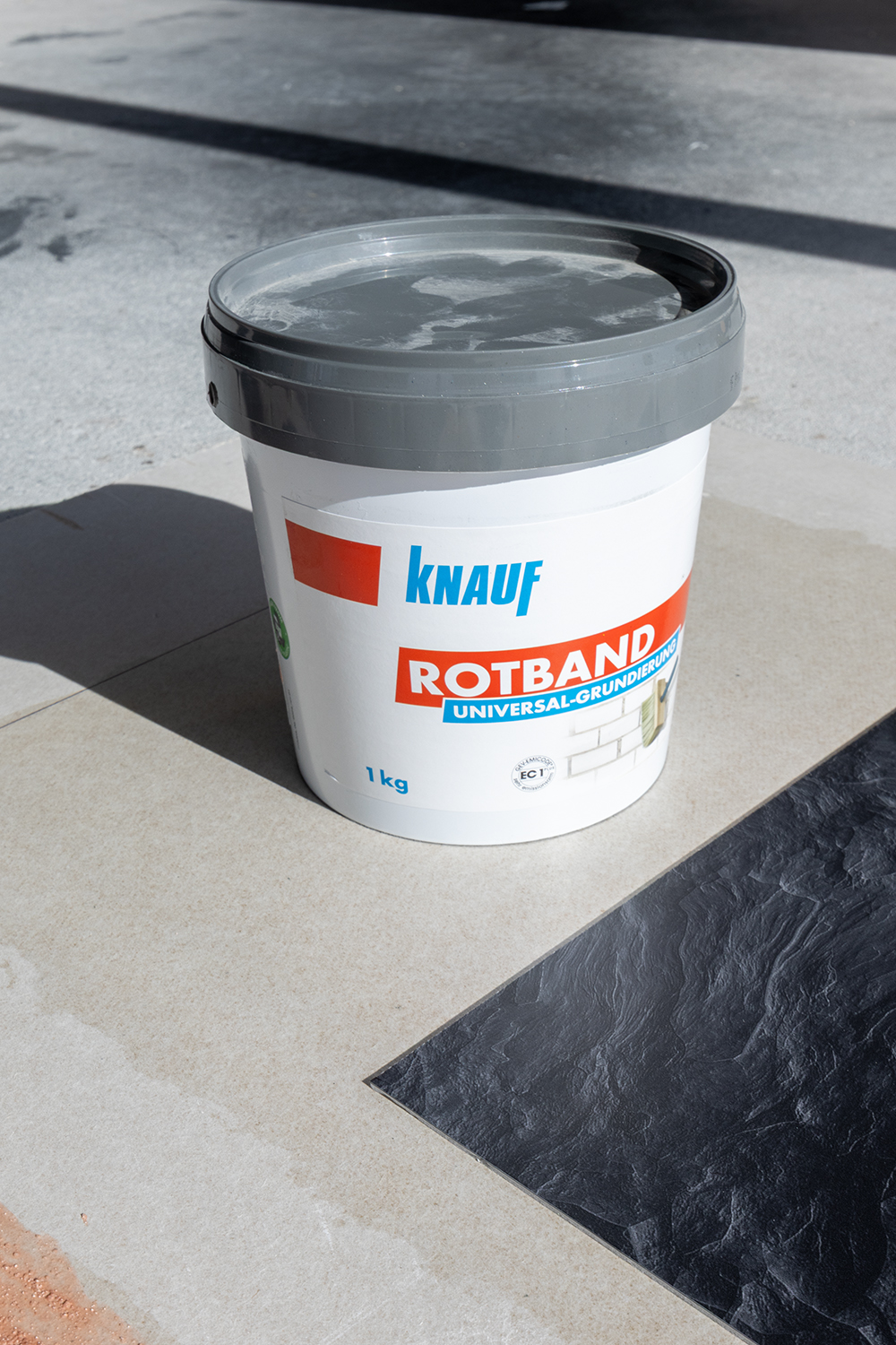 1Kg Becher Haftgrund steht auf grundierter Gripskartonplatte mit Kuechenrueckwand im Anschnitt